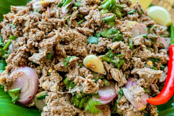 Thai beef larb salad with fresh shallots, herbs, and chili served on a banana leaf.