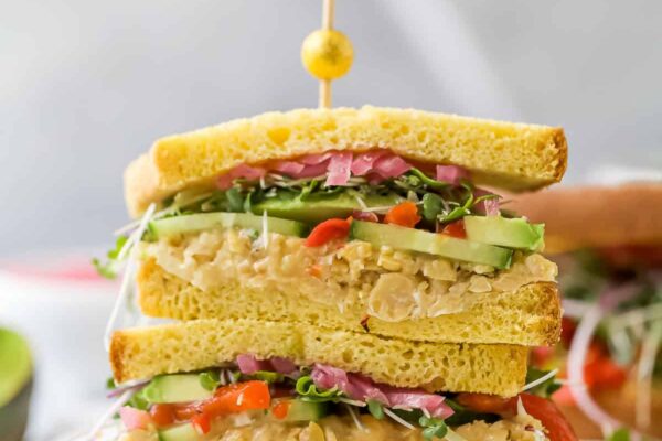 Two avocado sandwich halves stacked with toothpick and olive on top