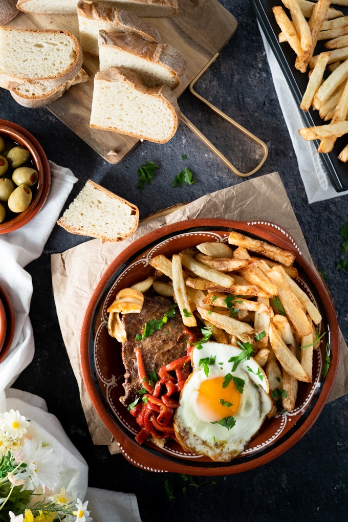 Red plate with steak, fries and an egg