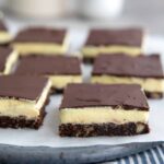 Keto Nanaimo bars arranged on white parchment over a rustic blue plate.