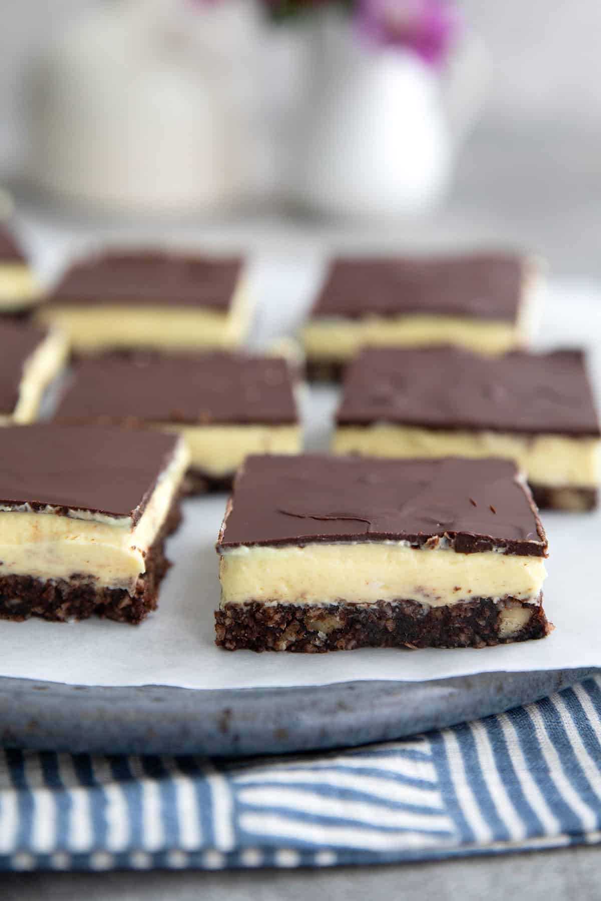 Keto Nanaimo bars arranged on white parchment over a rustic blue plate.