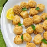 platter of breaded sea scallops garnished with basil leaves and lemon