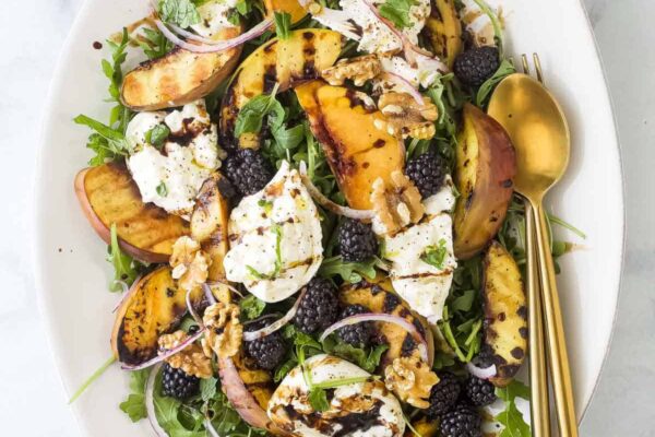 Burrata & Grilled Peach Salad Overhead view of burrata and grilled peach salad on platter with fork and spoon