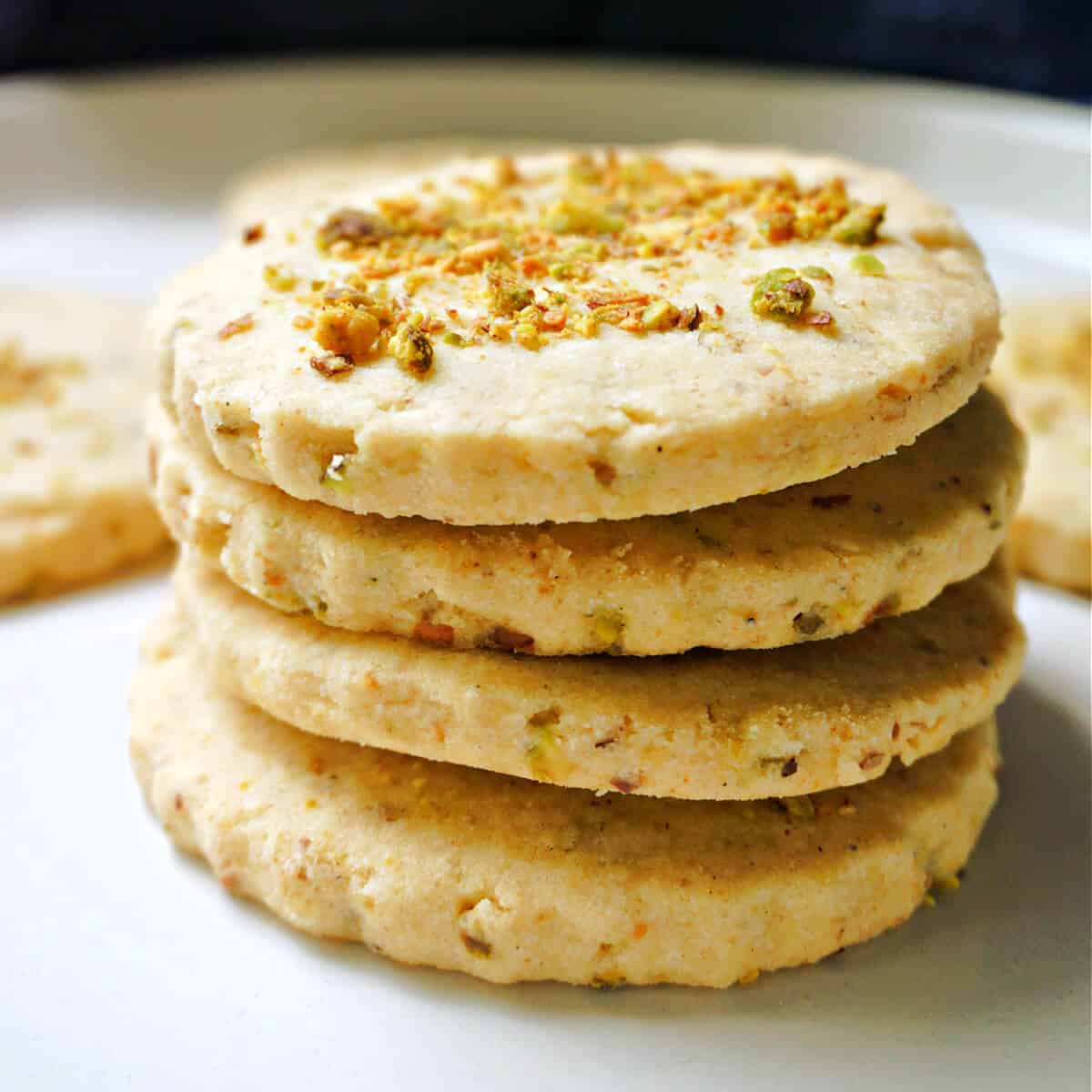 A stack of 4 cookies on a white plate.