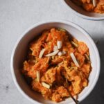 Close up of bowls of Carrot Halwa garnished with slivered almonds and pistachios ready to be eaten.