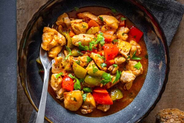 Turkish chicken dish with a tomato sauce served in a bowl and a fork inside it.