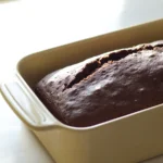 Freshly baked chocolate bread loaf in a pan, ready to be sliced.