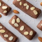 Candy bars topped with almonds on a tray.