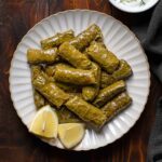 Dolmades, Greek stuffed grape leaves with rive on a plate. Featured.