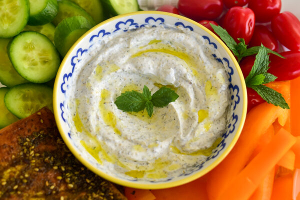 Easy 1 Minute Yogurt Dip (Healthy Recipe) yogurt dip with a mint sprig, olive oil drizzle, and veggies around it
