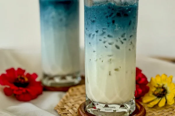 Two tall glasses of butterfly pea milk tea.