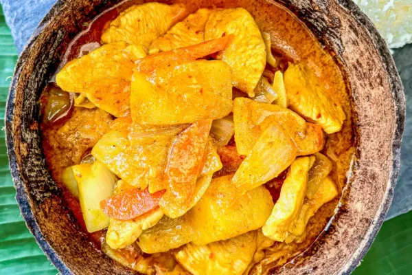 Thai gang garee curry featuring tender chicken and potatoes in a coconut shell.