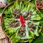 Overhead view of Thai ground beef lettuce wraps with larb filling and whole red chilies arranged on fresh lettuce.