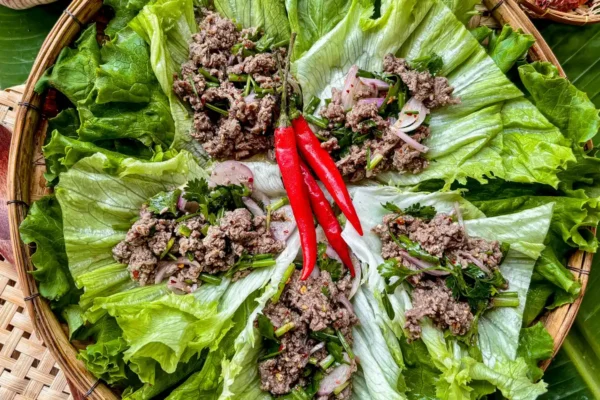 Overhead view of Thai ground beef lettuce wraps with larb filling and whole red chilies arranged on fresh lettuce.