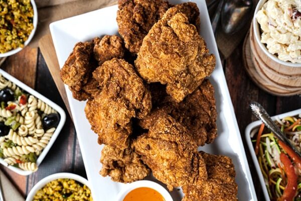 A large plate of chicken surrounded by side dishes