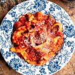 Trippa Finta (Italian omelette in tomato sauce) in a blue and white bowl sitting on a wooden surface.