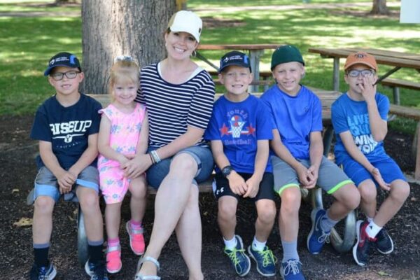 Mom with five kids sitting on bench.