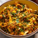Side image of cabbage sabzi served in a yellow bowl.