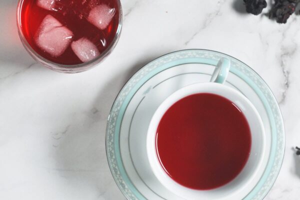 A cup of tea and a plate with dried hibiscus flowers.