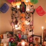 Day of the Dead altar at night: an ofrenda lit with candles, papel picado strung across the top, photos, sugar skulls and other items to celebrate All Saints and All Souls Day.