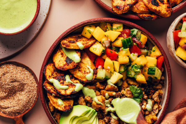 Jerk Tofu & Roasted Plantain Bowls Drizzling green tahini sauce onto a Jerk Tofu & Roasted Plantain Bowl