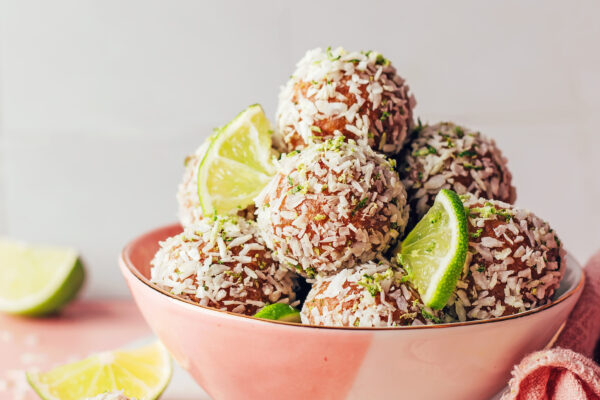 Bowl of no-bake coconut lime energy bites and lime slices