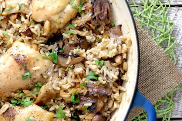 One pot chicken with mushroom rice overhead of wood table and loose mushrooms and parsley with clear photo of rice with mushroom and chicken
