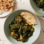 A blue bowl with Palak Chicken and naan ready to be eaten.