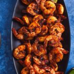 Tandoori shrimp tikka served on a black oval platter.