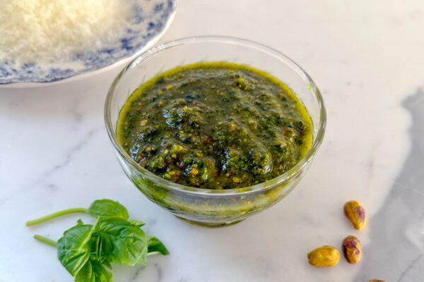 pistachio pesto in a glass dish on a marble countertop
