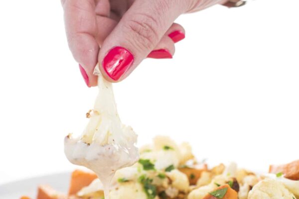 Dipping roasted vegetables in tahini lemon sauce.