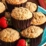 A teal platter stacked with two layers of strawberry rhubarb muffins. The plate is garnished with fresh berries.
