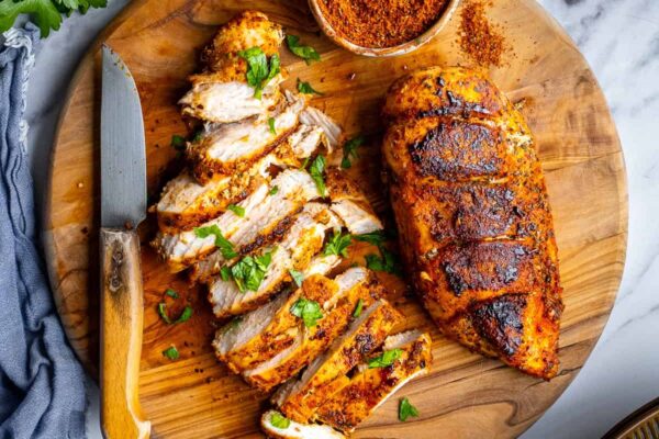 Turkish Chicken Breasts (Pan-Fried) – Give Recipe Pan-fried chicken breasts on a round wooden cutting board and a spice mix in a small bowl on the side.