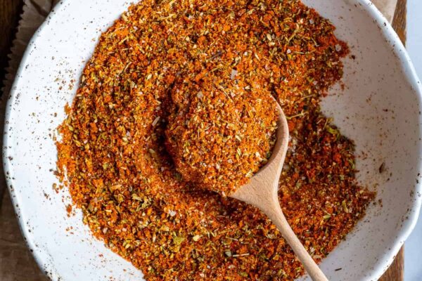 Turkish spice mix in a white bowl and a wooden spoon inside it.