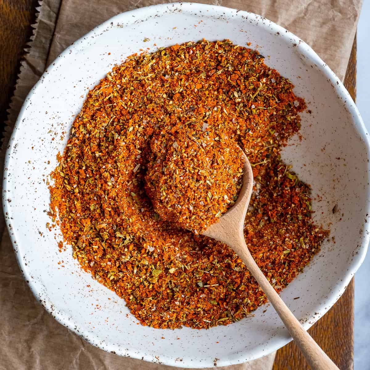 Turkish spice mix in a white bowl and a wooden spoon inside it.