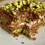 no bake dubai chocolate cake closeup of the layers of cream, chocolate biscuits and kataifi pistachio
