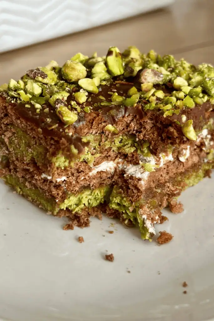 no bake dubai chocolate cake closeup of the layers of cream, chocolate biscuits and kataifi pistachio