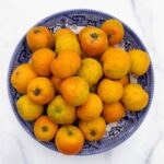 Tejocotes, also known as Mexican hawthorn, in a blue and white ceramic bowl over a white marble countertop