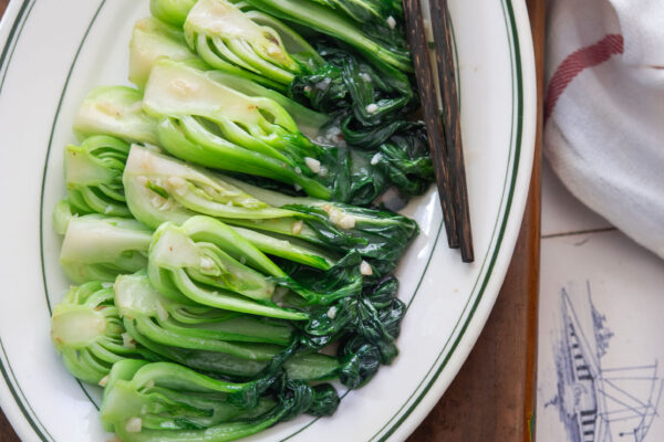 Stir-fried bok choy with garlic and light savory sauce, served on a white plate.