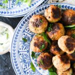 a plate of chicken keftedes on a blue plate with a side of tzatziki.