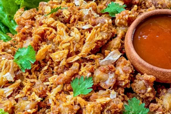 Fried Chicken Knuckles Recipe (En Kor Gai Tod) Fried chicken knuckles, garnished with fried garlic and coriander, served with Thai hot sauce.