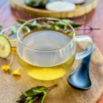 Glass cup of holy basil tea with honey and lime on a wooden board.