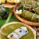 Khao tom mud, Thai sticky rice banana dessert, presented in banana leaves and a bamboo basket.