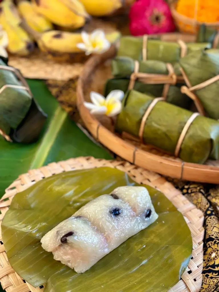 Khao tom mud, Thai sticky rice banana dessert, presented in banana leaves and a bamboo basket.