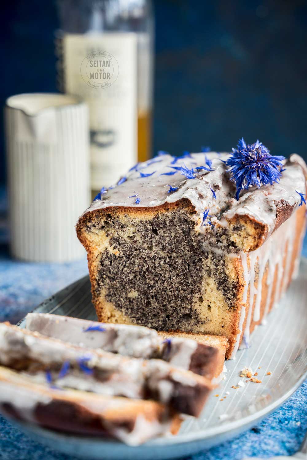 A poppy seed marzipan cake in the box on a serving plate. The cake is cut and you can see the marble.