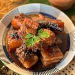 Overhead shot of Thai pork belly stew, moo hong, with dark soy sauce, cinnamon, and coriander in a patterned bowl.