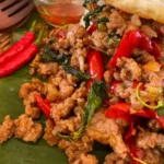 Pad kra pao moo served with rice, a fried egg, prik nam pla, and lots of chilies.