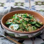 Spicy peanut cucumber salad topped with chopped peanuts and cilantro in a ceramic bowl
