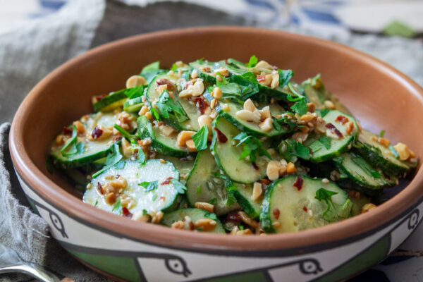 Spicy peanut cucumber salad topped with chopped peanuts and cilantro in a ceramic bowl
