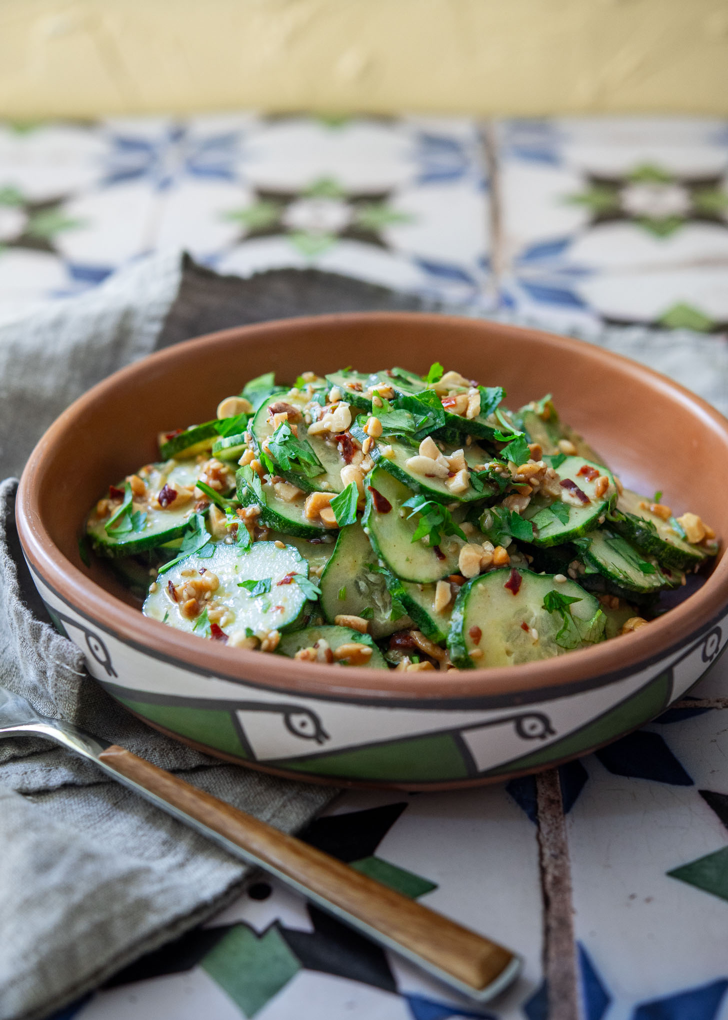 Spicy peanut cucumber salad topped with chopped peanuts and cilantro in a ceramic bowl
